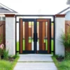 A modern, elegant garden gate with a sleek metal frame and wooden accents, installed in a well-maintained suburban yard with green grass, flowering shrubs, and a paved path leading to it. The gate is closed but inviting, with soft natural daylight, no people, no text, no signs, no logos, no vehicles, no clutter — just the gate and its peaceful surroundings.