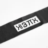 A close-up of a black electrical insulation tape labeled 'ЛЭТСАР' on a white background, showing the tape's texture, adhesive side slightly lifted, and clear Cyrillic text 'ЛЭТСАР' printed along its length, no shadows or reflections, high detail, smallHQ style