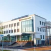 A modern oncology center building with high-quality electrical supply, showing clean energy infrastructure like solar panels on the roof, underground power cables, and a reliable electrical substation nearby, all under a clear sky, emphasizing safety, technology, and healthcare excellence
