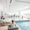 A modern medical wellness and rehabilitation center with bright, clean interiors, featuring therapy rooms, exercise equipment, hydrotherapy pools, and patients receiving care from doctors and physiotherapists in a calm, professional environment, natural lighting, soft colors, and a sense of healing and recovery